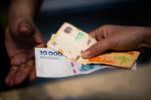 manos sosteniendo bonos financieros argentinos